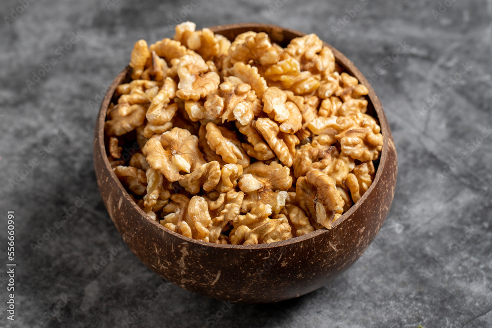 Walnuts in a bowl on a dark background. Walnuts in a coconut bowl. close up Walnuts in a bowl on a dark background. Walnuts in a coconut bowl. close up