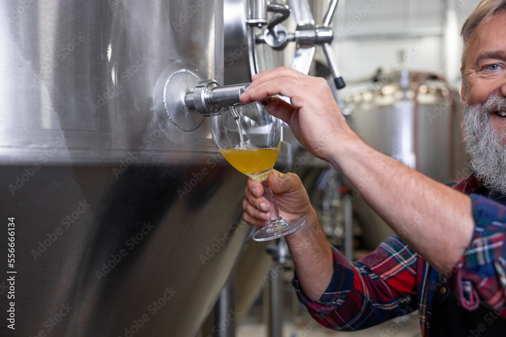 Brewery worker pouring fresh beer into the glass Brewery worker pouring fresh beer into the glass