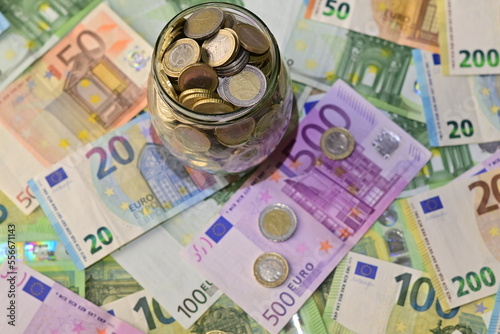 Coins in a glass jar and Euro banknotes bills on the table. The concept of investment, interest.Coins in a glass jar and large Russian bills on the table. The concept of investment, interest.