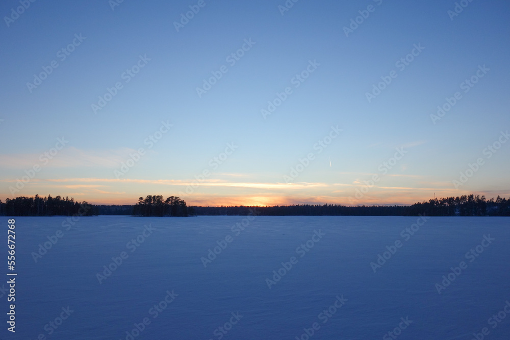 Sunset over the snowy frozen lake 