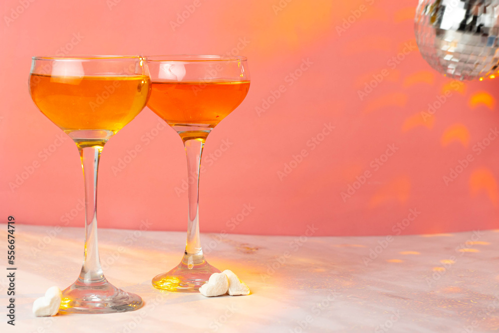 Orange cocktail with tall glasses on a pink background. Two glasses