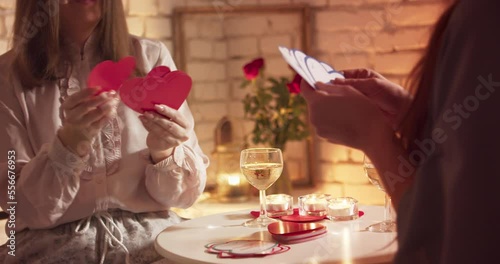 Two young women are playing cards. Playing cards in the shape of a heart. Valentine's Day concept photo