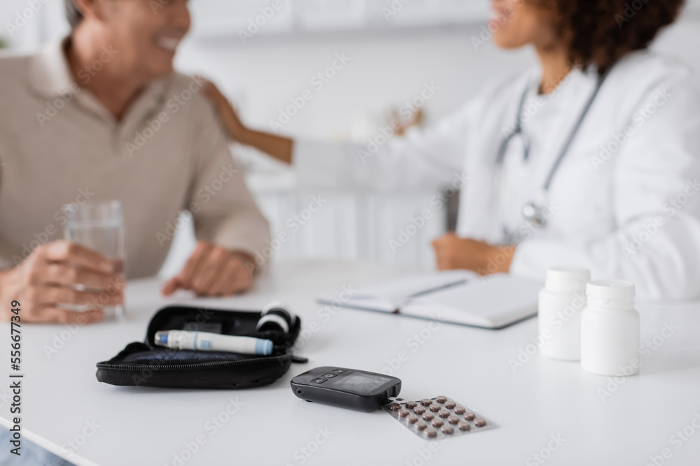 diabetes kit with glucose meter and lancet pen devices near african american doctor and patient on blurred background diabetes kit with glucose meter and lancet pen devices near african american doctor and patient on blurred background