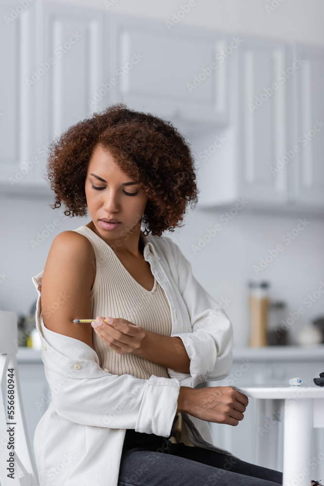 African american woman with diabetes doing insulin injection near lancet pen in kitchen African american woman with diabetes doing insulin injection near lancet pen in kitchen