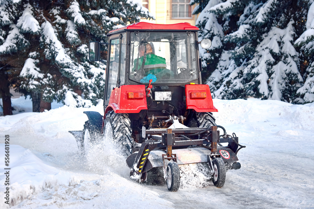 Tractor sweep snow with brush after snowfall. Snowblower vehicle cleans sidewalks. Tractor remove snow from sidewalk. Snow plow and removal service. Tractor cleaning snow in city park after blizzard. Tractor sweep snow with brush after snowfall. Snowblower vehicle cleans sidewalks. Tractor remove snow from sidewalk. Snow plow and removal service. Tractor cleaning snow in city park after blizzard.