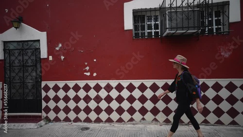 Pretty, mature, woman walking on a sidewalk along colorful buildings in Merida, Yucatan, Mexico. photo