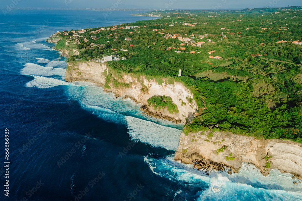 Aerial view of coastline with cliffs, ocean with waves and lighthouse in Uluwatu, Bali