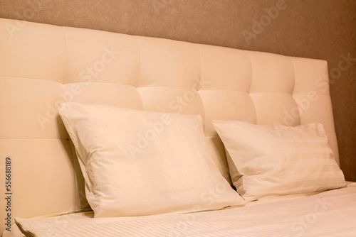 a bed with a high leather headboard and pillows