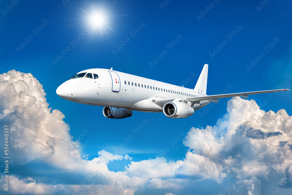 White passenger airliner fly in the air above picturesque clouds