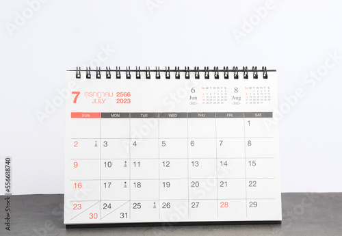 month July 2023 desk calendar for planners and reminders on a black table on a white background. 