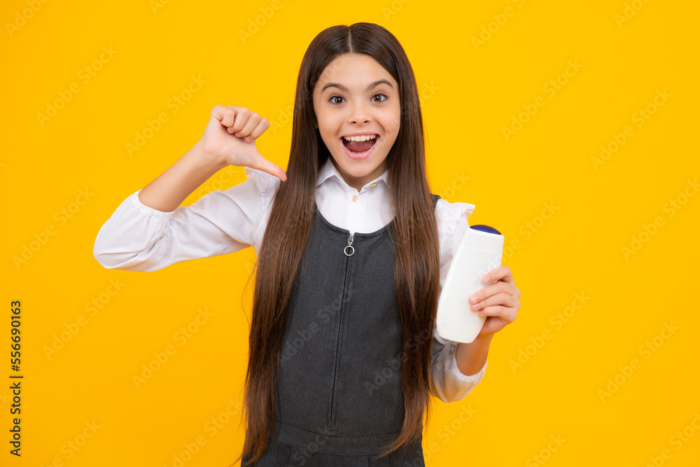 Amazed teen girl. Teenager child girl showing bottle shampoo conditioners or shower gel isolated on yellow background. Hair cosmetic product. Mock up bottle. Excited expression.