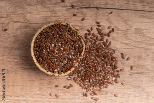 flax seeds in a wooden bowl on a wooden background, top view