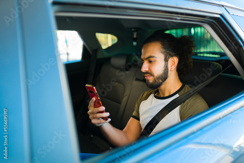 Latin passenger using his smartphone for a ride share service