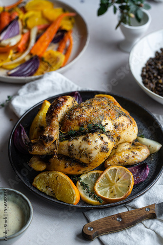Dinner with oven baked spring chicken (coquelet jaune) in French herbs and citruses, baked vegetables and lentils on white background.