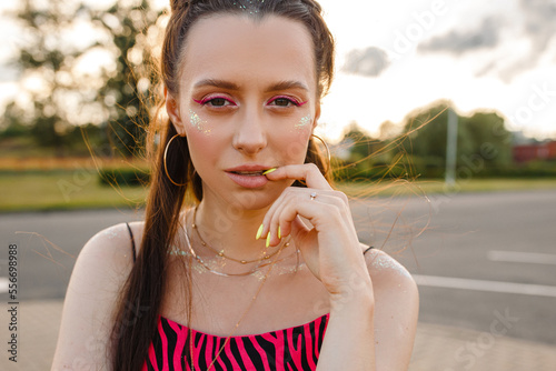 Fotografie Portrait of confident young female teenager with glitter on face looking at came