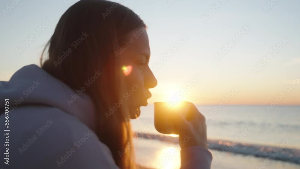 Cool Sunrise on the Sea. The Girl Holds A Metal Mug with A Hot Drink. She blows on him. The rays of the Sun directly into the camera.