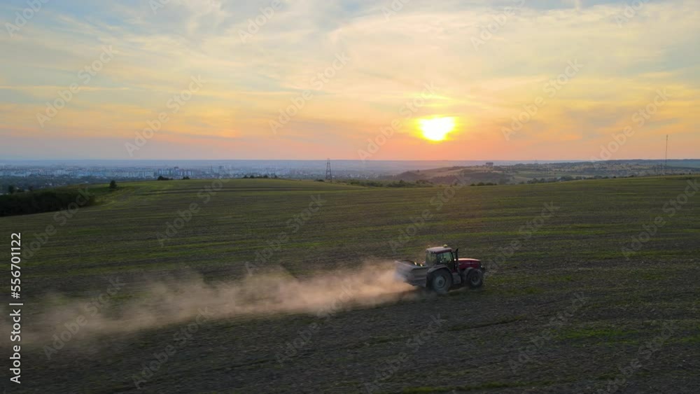 Tractor spraying fertilizers with insecticide herbicide chemicals on agricultural field at sunset Tractor spraying fertilizers with insecticide herbicide chemicals on agricultural field at sunset