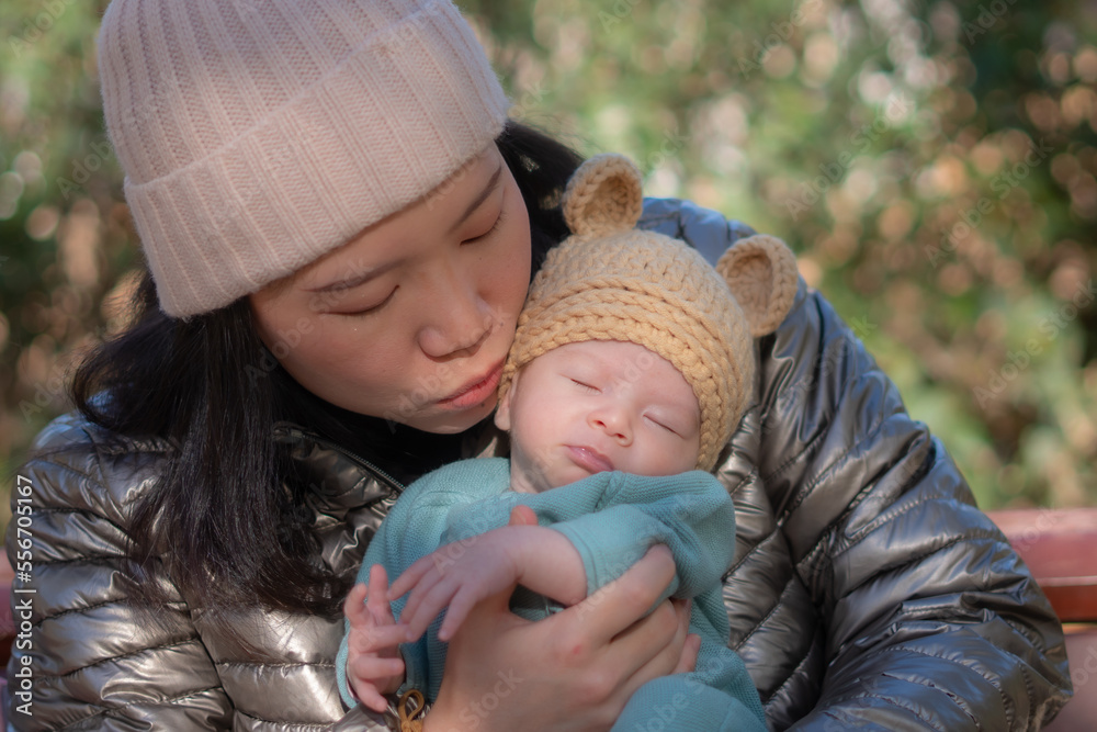 Obraz premium outdoors lifestyle portrait of young happy and beautiful Asian Chinese woman as mother of little adorable baby girl holding her tender and sweet in city park on sunny day