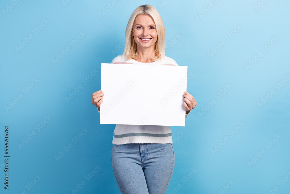 Photo of adorable stunning lady hold paper sheet demonstrates empty space recommend modern device shop isolated on blue color background Photo of adorable stunning lady hold paper sheet demonstrates empty space recommend modern device shop isolated on blue color background