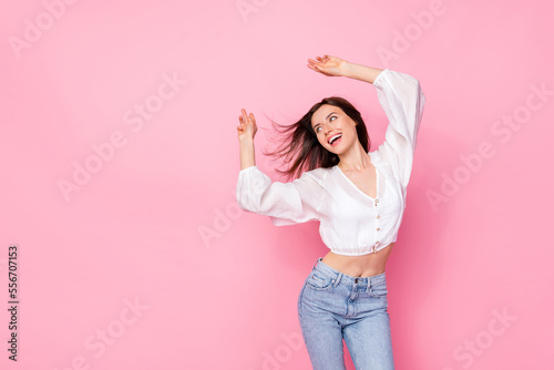 Photo portrait of pretty young girl dancing look empty ad space feel free dressed stylish white outfit isolated on pink color background