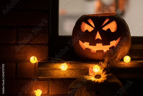 Obraz na płótnie Spooky Halloween pumpkin, Jack O Lantern with pumpkins lights hanging from a win