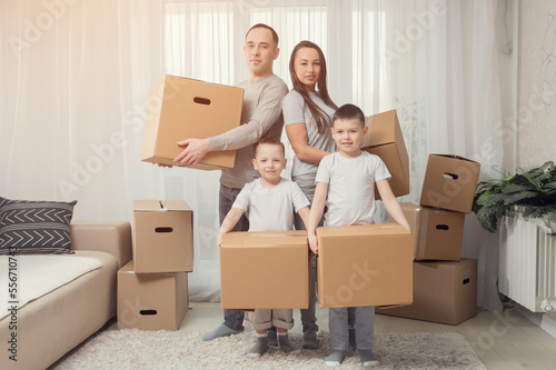 A happy family with children moves with boxes to a new apartment building, sunlight