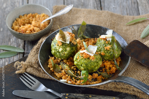 Deftige Südtiroler Spinatknödel mit Salbei, Butter und gebräunten Parmesan-Semmelbröseln im Pfandl serviert - South Tyrolean spinach bread dumplings with sage leaves and fried cheese breadcrumbs