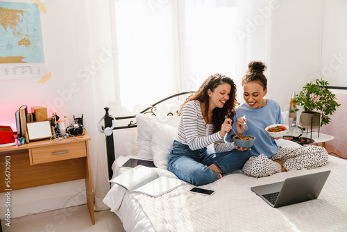 Wallpaper Mural Cheerful young women using laptop and having breakfast in bed at home Torontodigital.ca