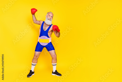 Full size photo of handsome sportive person wear boxing gloves soft fluffy belt look empty space isolated on yellow color background