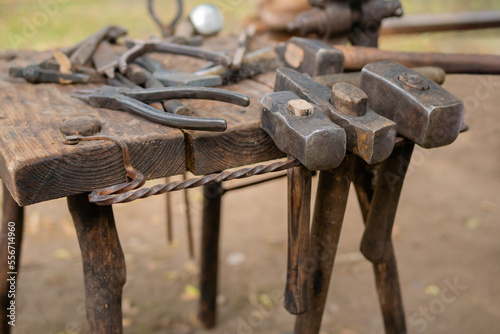 Blacksmith tools and instruments on wooden workbench, table at outdoor forge, workshop - close up. Handmade, craftsmanship and blacksmithing concept
