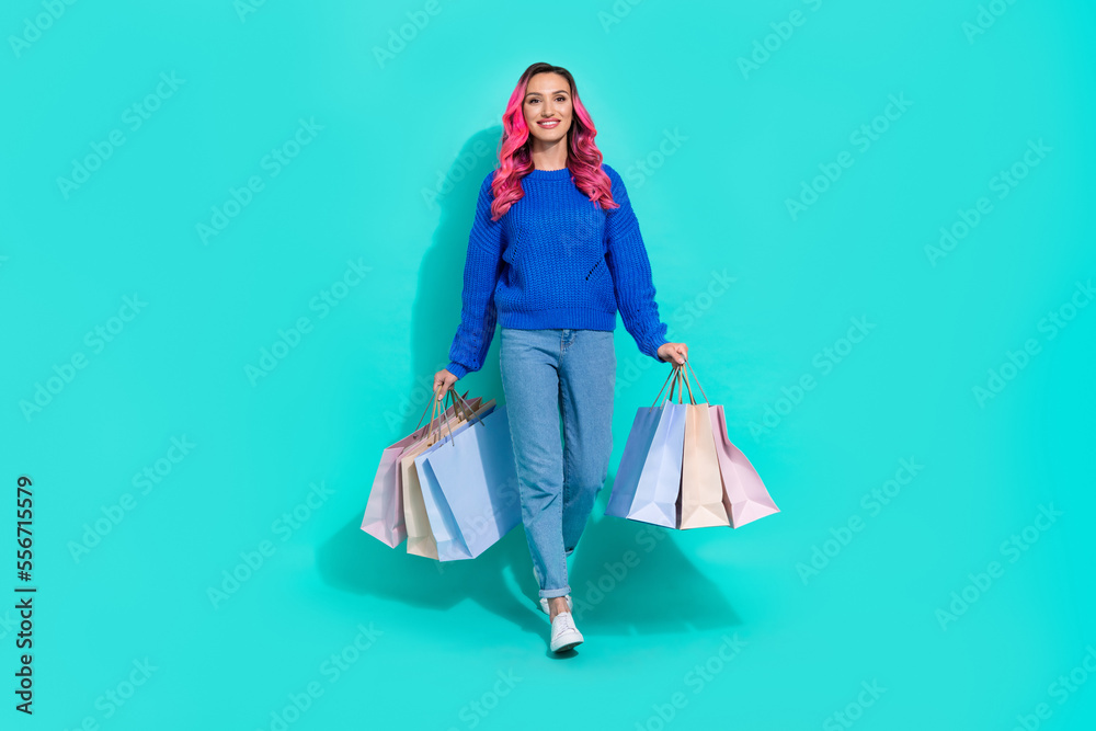 Full body length photo of young beautiful girl wear modern casual style clothes walk shopping mall bargains isolated on aquamarine color background Full body length photo of young beautiful girl wear modern casual style clothes walk shopping mall bargains isolated on aquamarine color background