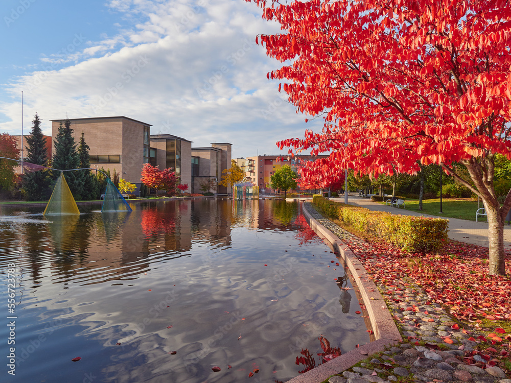 City European public park with fountains in the Finnish town of Kerava: reflections of clouds, city buildings, sunny autumn day.