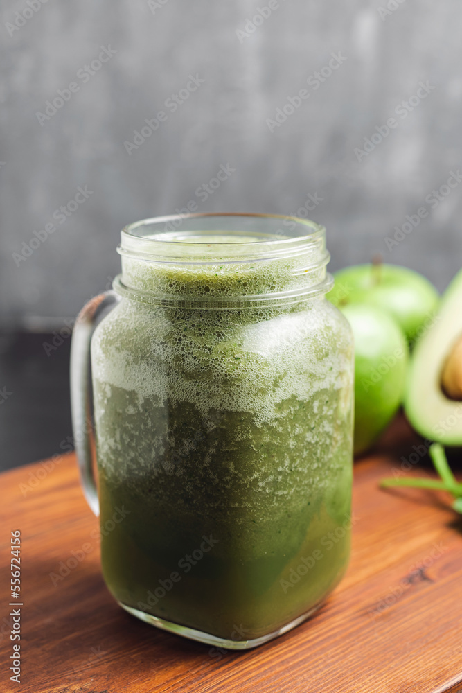 Green smoothie drink blended in a glass jar, avocado, spinach leaves and apples at wooden board Green smoothie drink blended in a glass jar, avocado, spinach leaves and apples at wooden board