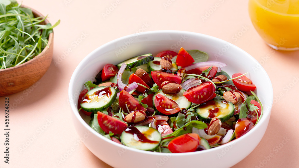 Healthy salad with spelt, oranges, pomegranate seeds. greens and nuts on light background, minimal style