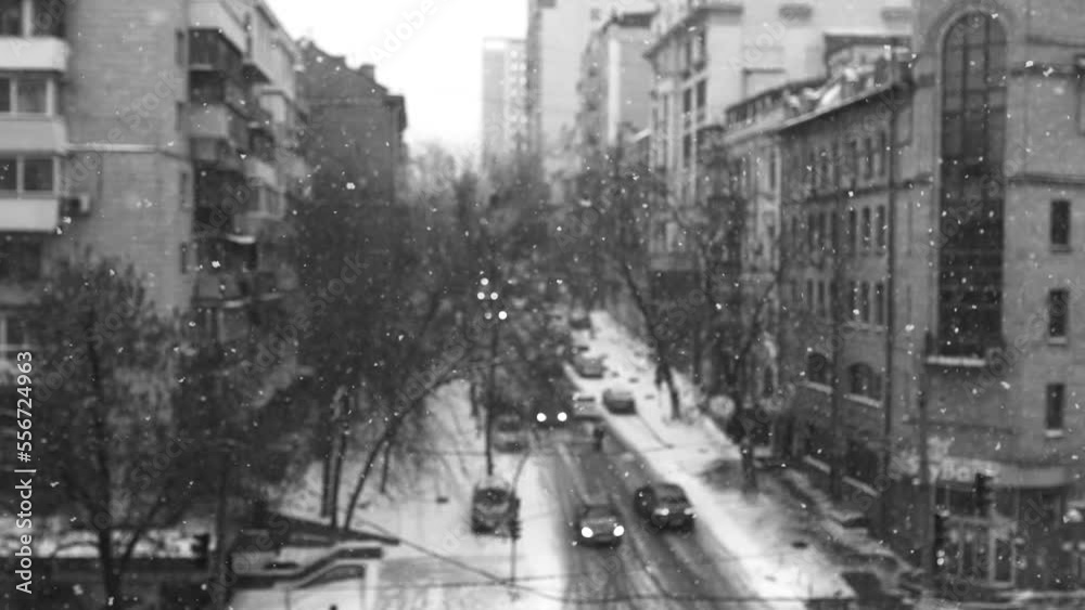 View of a snowy city street during a snowfall. View of a snowy city street during a snowfall.