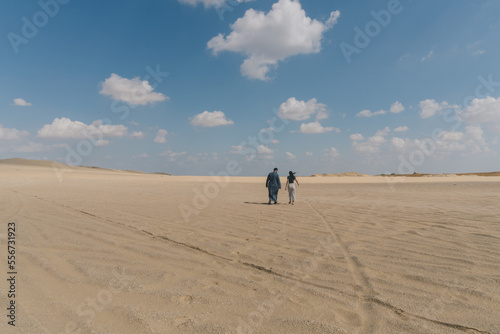 A young couple walking alone through the Fayoum desert in Egypt.