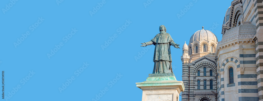 Banner with statue of a Bishop Henri de Belsunce at magnificent Cathedral de la Major in Marseille at blue sky solid background with copy space, Marseille, France.