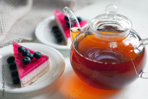 teapot with hot black tea and cake on plate with berries. afternoon tea beverage and sandwich sweet photo