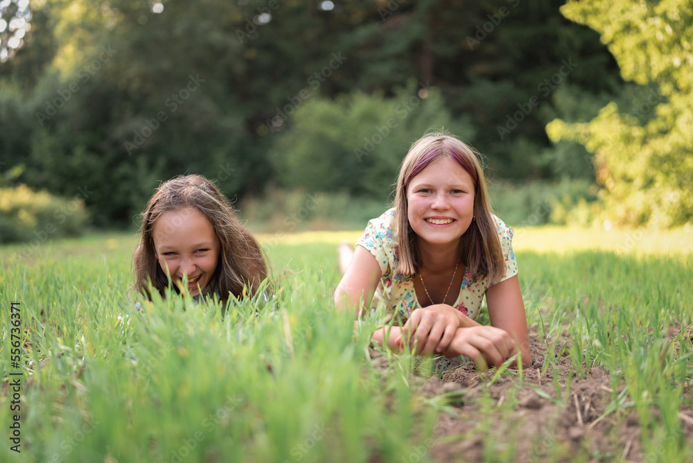 Two beautiful young girls lie on the grass in a summer field. Two beautiful young girls lie on the grass in a summer field.