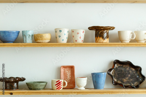 Fotografi Handmade ceramic crockery and craft pottery jug, jars and cups standing on shelves in creative studio or potter store