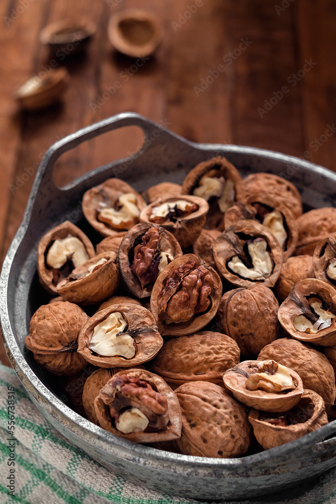 Obraz premium Organic walnuts in a bowl on a wooden backgound.