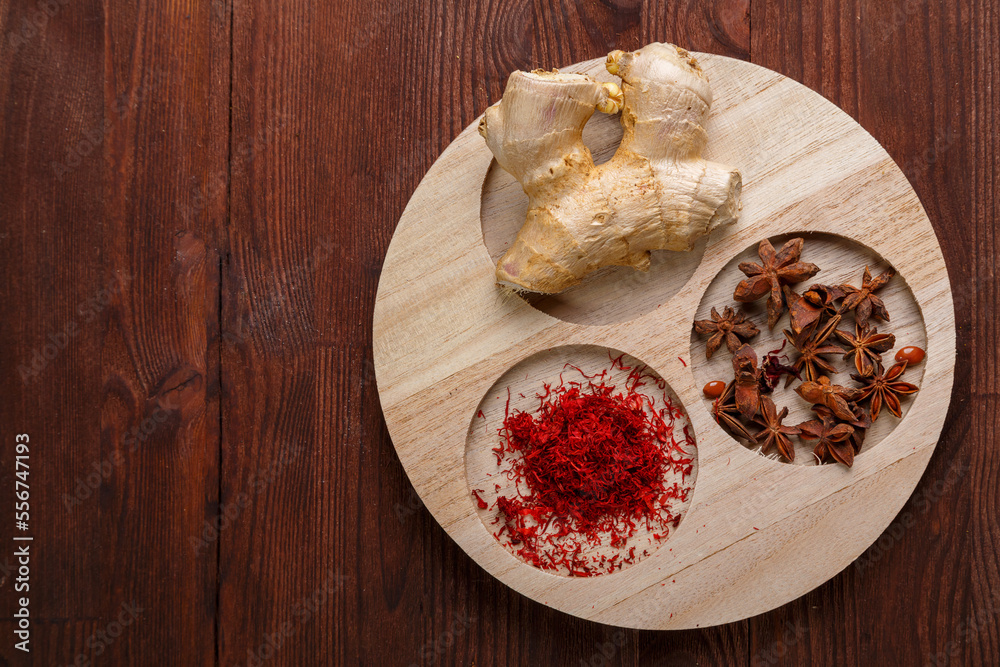 Spices ginger, saffron and anise on a round wooden bowl on the table.copy space