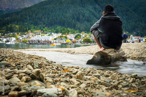 A man sits and reflects on the shores of Queenstown's Lake Wakatipu; Queenstown, Otago, New Zealand photo