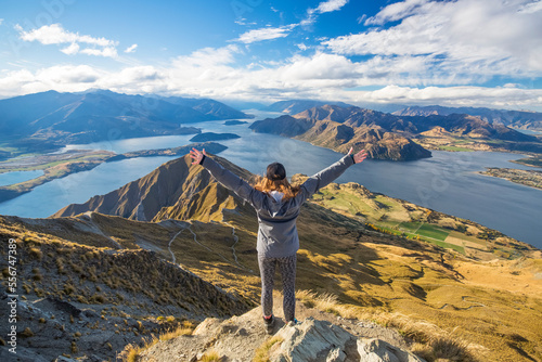 The strenuous yet highly rewarding hike to Roys Peak in Wanaka. The hike is difficult but the views are spectacular. A traveler celebrates at the summit; Wanaka, Otago, New Zealand photo