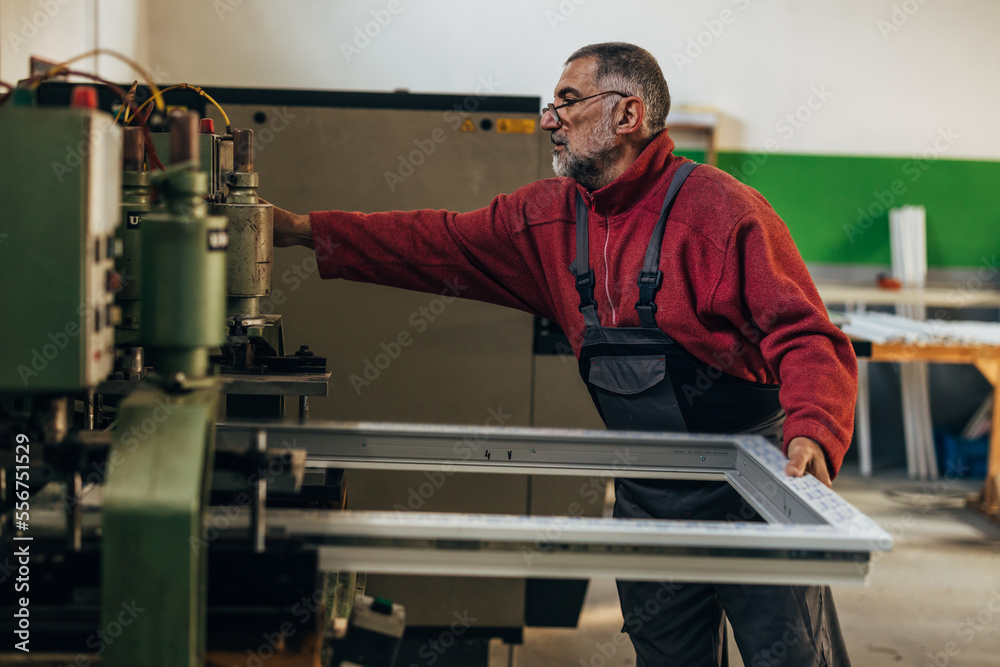 Man puts the window frame in the machine and presses the button Man puts the window frame in the machine and presses the button
