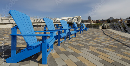 Public plaza with blue, Muskoka chairs in a row at the Johnson Street Bridge; Victoria, British Columbia, Canada