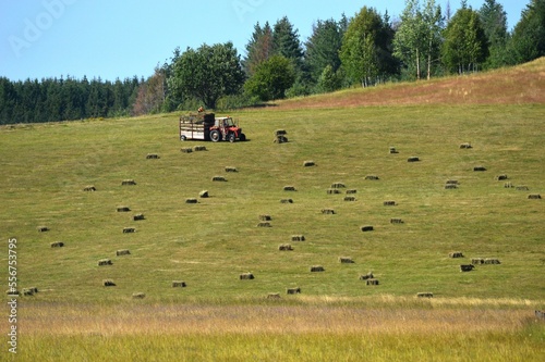 a tractor is gathering hay on the slope