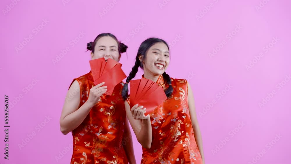 4K, portrait, Two Asian girls wearing red Chinese national costumes (cheongsams), Both of them were holding red envelopes, several envelopes in their hands, Isolated indoor studio on blue background. 4K, portrait, Two Asian girls wearing red Chinese national costumes (cheongsams), Both of them were holding red envelopes, several envelopes in their hands, Isolated indoor studio on blue background.