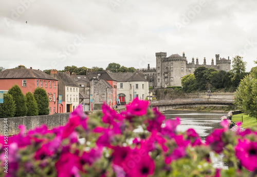 Purple garden flowers in front of John's Bridge and the River Nore that flows through the city of Kilkenny with its 12th Century Kilkenny Castle in the background; Kilkenny, County Kilkenny, Ireland photo