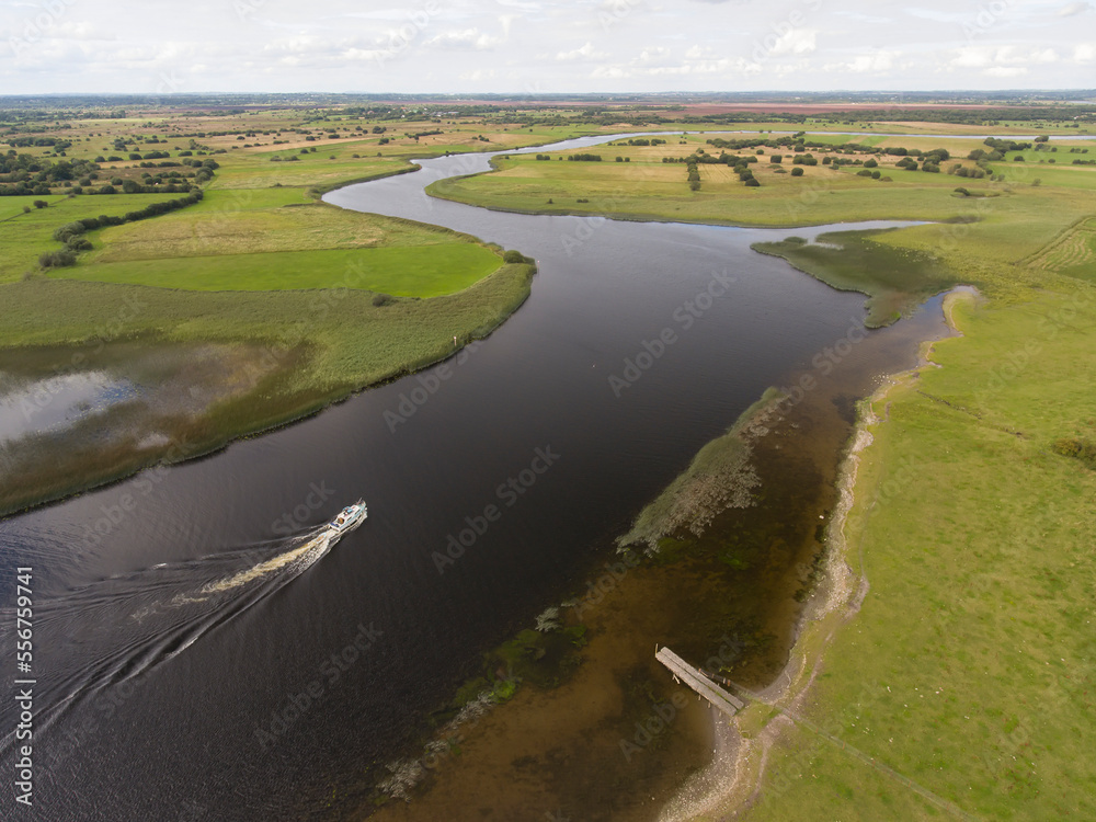 Aerial view of a boat exploring River Shannon along the banks of the Clonmacnoise ruins; County Offaly, Ireland Aerial view of a boat exploring River Shannon along the banks of the Clonmacnoise ruins; County Offaly, Ireland